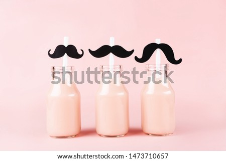 Three bottles of drink with funny straws on pink background. Pik yogurt, strawberry milk, smoothie or other beverage.