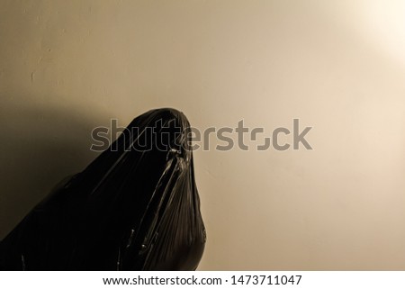 Man With Black Plastic Bag Pulled Tightly Over His Face. Concept of Suffocation and Death. Dark Stock Photo.
