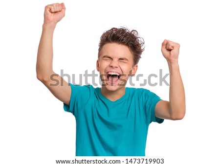Portrait of successful teen boy winner with raised hands and clenching fists. Beautiful caucasian teenager shouting, isolated on white background. Happy cute child celebrating success with joy. Royalty-Free Stock Photo #1473719903