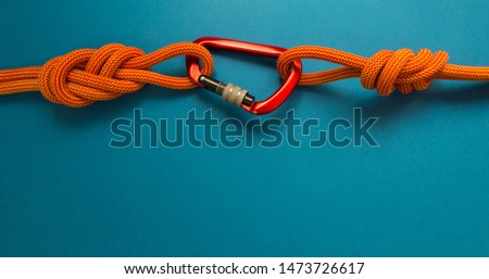 Red carbine with clutch. Equipment for climbing and mountaineering. Safety rope. Knot eight.
