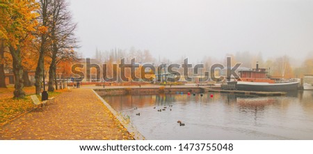 Lappeenranta port with boat at autumn day. Sights of Lappeenranta harbor and garden, beautiful fall tree yellow leaves amazing view. October autumn park foliage and lake fog scene, travel in Finland