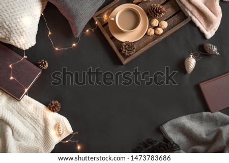 Christmas coziness concept. Seasonal winter composition with soft plaid, coffee and book. Cozy home and hygge concept, copy space.