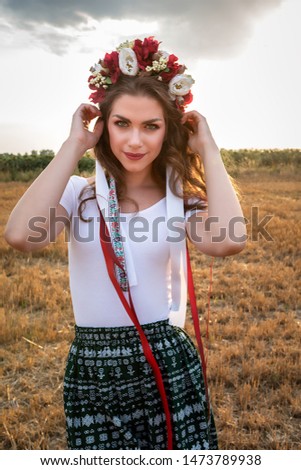 Beautiful woman in Slovakia nature sunset, Young girl with traditional Slovakia folklore costume at the agricultural wheat field after harvest time with industrial combine machine beautiful headband