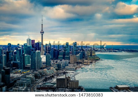 TORONTO CITY SKYLINE IN WINTER - Aerial scene of downtown Toronto with business buildings and condo housing from airplane. Frozen Canadian cityscape, dense urban core and waterfront. Ontario, Canada