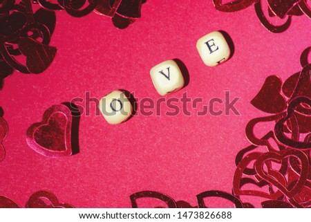 Word love, wooden cubes letters, on a red background whit red hearts