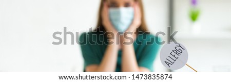 panoramic shot of woman in medical mask propping face with hands and nameplate with inscription allergy