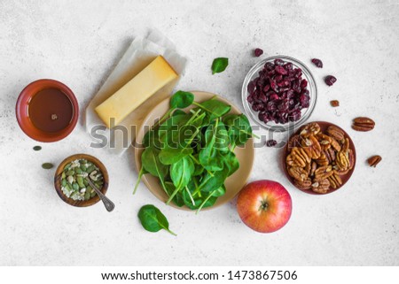 Healthy Autumnal Salad Ingredients for cooking healthy seasonal salad - baby spinach leaves, apple, pecan nuts, dry cranberries, honey on white background, copy space.