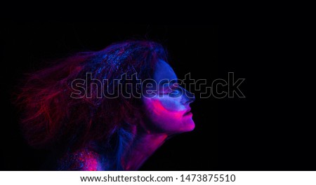 Face of a girl in neon colors. Art design of female posing in UV. Portrait of Beautiful Fashion Woman in Neon UF Light.