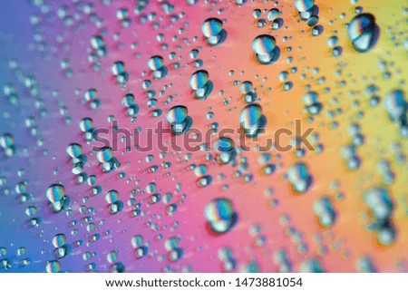Water drops with reflection of the rainbow. Colorful abstract background. Blue, green, red and yellow abstract rainbow background. Closeup, selective focus
