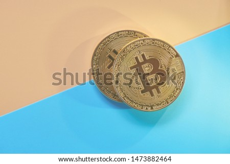 Physical gold coins bitcoins on a yellow blue background. Digital cryptocurrency concept