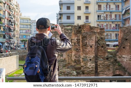 Young man, tourist, with backpack taking picture on a smartphone the Palace of Galerius. Palace of Galerius are the parts of the complex of the Roman emperor Galerius in the Thessaloniki, Greece.