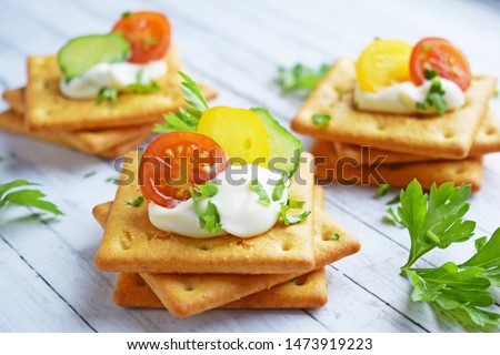 Delicious crackers with cheese sauce and vegetables.Snack on wooden background. Royalty-Free Stock Photo #1473919223