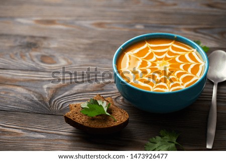 A healthy pumpkin puree garnished with cream and parsley leaves. Autumn cream soup for the holiday Halloween on a dark wooden background