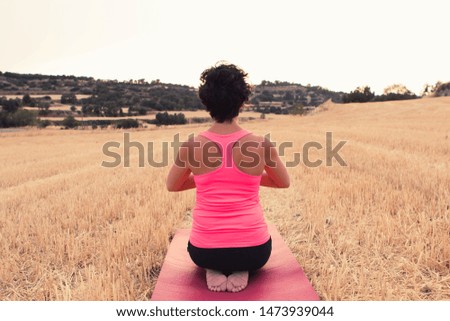 Young girl doing yoga in the middle of a wheat field. Meditation and relaxation concept.