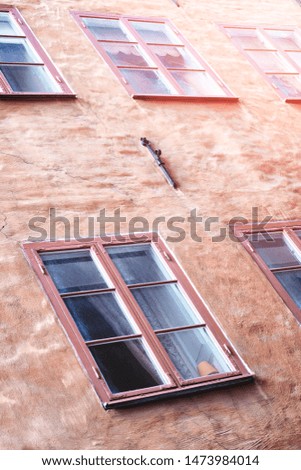Part of the facade of a red historic building illuminated, reflecting off window panes, in the Old Town Gamla Stan of Stockholm, Sweden. Series - streets of old stockholm