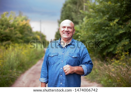 Portrait of  senior farmer in   denim shirt in   village. Royalty-Free Stock Photo #1474006742