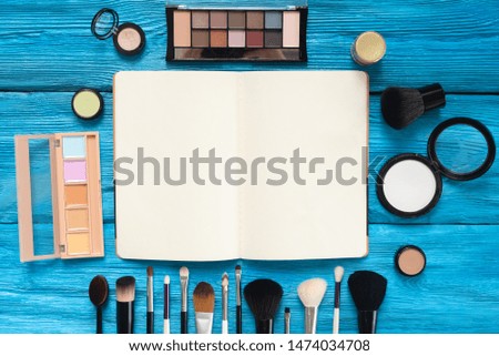 Makeup blank page handbook with a copy space and various cosmetic on blue wooden table background.