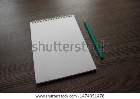 notebook and pencil on wooden background