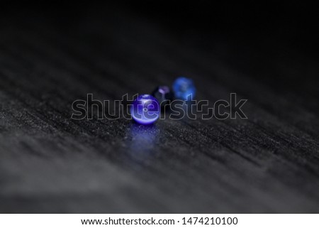 Three blue beads on a black surface with black background