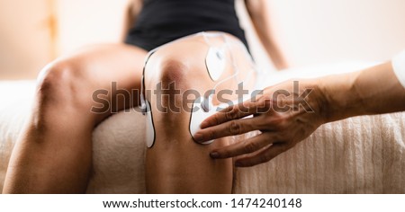 Knee Physical Therapy with TENS Electrode Pads, Transcutaneous Electrical Nerve Stimulation. Therapist Positioning Electrodes onto Patient's Knee Royalty-Free Stock Photo #1474240148