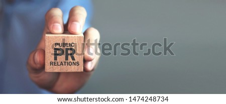 Man holding wooden cube. Pr- Public Relations