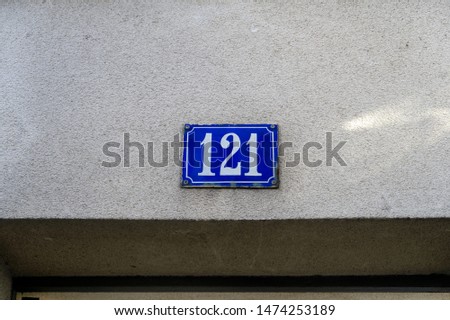 Number 121, street number plate on a facade.