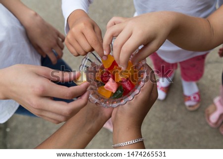 the child hold the colorful candies in the bowl service old humans for Muslim holidays, victim festival , mother or teacher day.