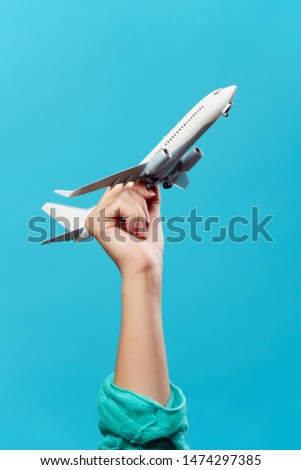 Image of hand with toy plane on empty blue background