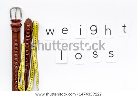 weight loss text with belt and measuring tape on white background top view