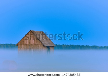 Old barn in a layer of evening fog during a summers evening 