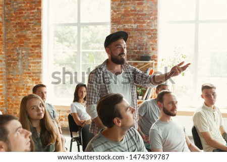 Male speaker giving presentation in hall at university workshop. Audience or conference hall. Student asking a question, teacher giving an answer. Scientific conference event, training. Education.