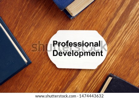 Text sign showing Professional Development. The text is written on a small wooden board. Conceptual photo shows colored papers, markers, wooden background.