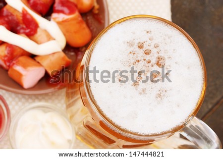 Beer and grilled sausages on wooden background