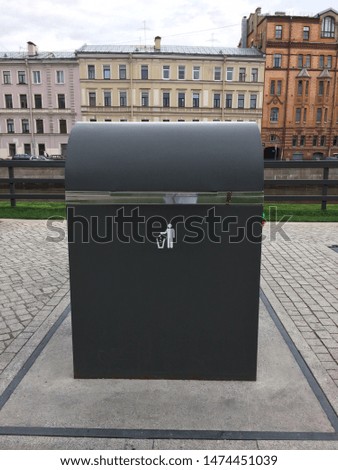 A picture of dustbin next to the street, which people can use for waste disposal. Metal Trash Can with Litter icon, white Litter Symbol on Dustbin.