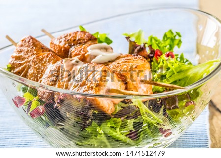 Grilled salmon skewers with summer lettuce salat pomehranate seeds olive oil and dressing. Healthy fish food with fruit and vegetable.