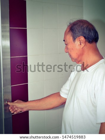 Asian senior man finger pressing the button in the elevator, selective focus.