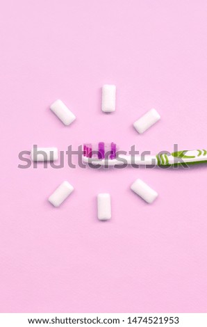Toothbrush and chewing gums lie on a pastel pink background