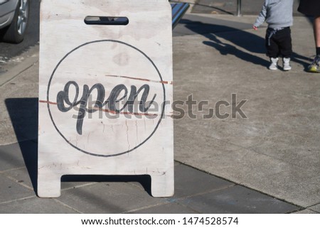 Open sign displayed on sidewalk outside business premises
