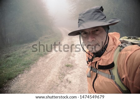 hiker with hat taking a selfie along a misty path in Nebrodi Park, Sicily 