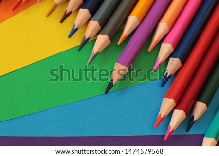 Colored pencils for drawing and creativity on a bright rainbow background school equipment of a real artist