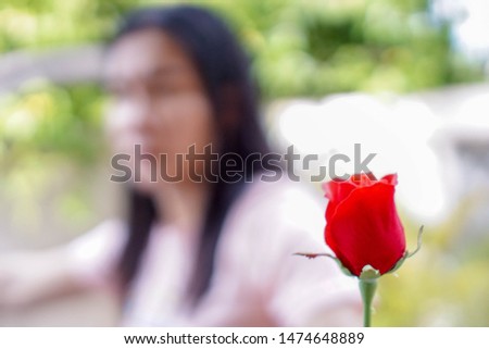 Red roses in the hands of men have blurred women as the background. The idea of ​​reconciliation with fans