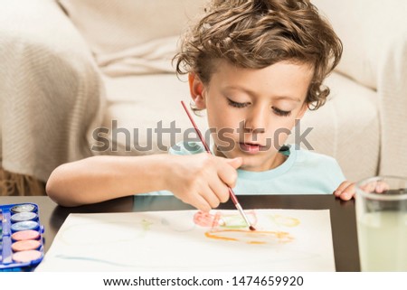Child painting with watercolors on paper. Concepts back to school and childhood.