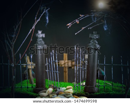gloomy dark entrance to the toy cemetery. Through the trellised gates on the green grass, wooden crosses are visible