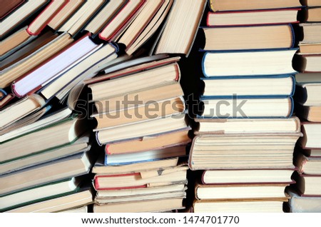 Heap of assorted retro hardcover books casually lies in stacks as background front view
