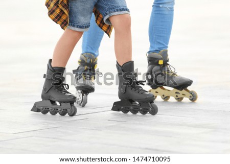Father and son roller skating on city street, closeup of legs