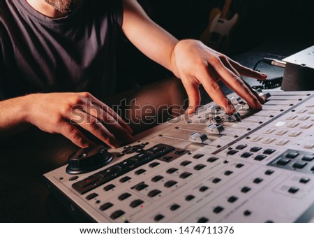 Unrecognizable sound producer or engineer rotates scrolls wheel on mixing console in professional recording studio. Musician working on new song. Hands close up.