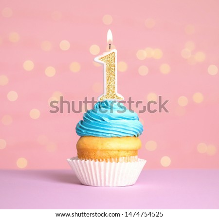 Birthday cupcake with number one candle on table against festive lights Royalty-Free Stock Photo #1474754525