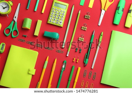 Green school stationery on red background, flat lay