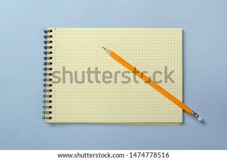 School notebook on a blue background. Spiral notepad on a table with a pencil