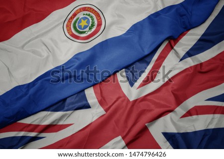 waving colorful flag of great britain and national flag of paraguay. macro